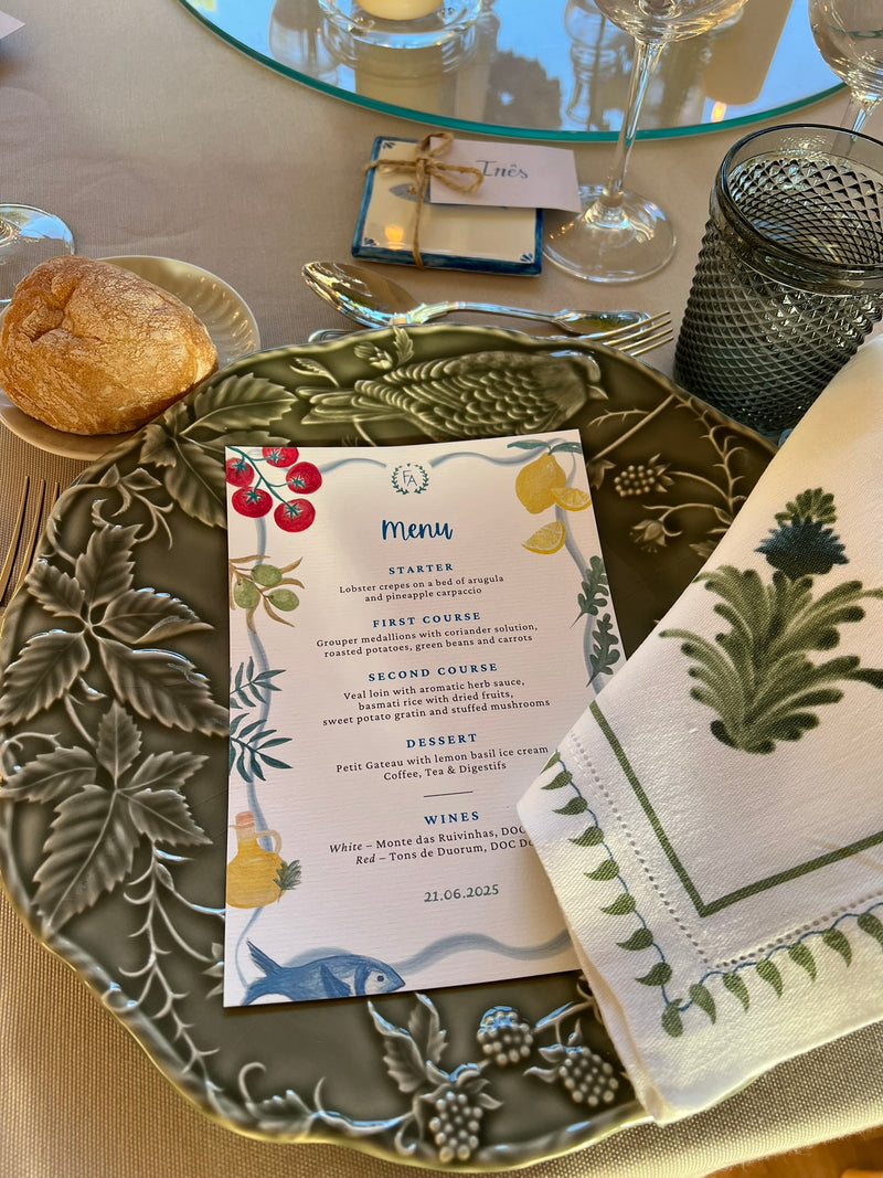 Table setting with a handpainted menu card, bread, and patterned napkin.