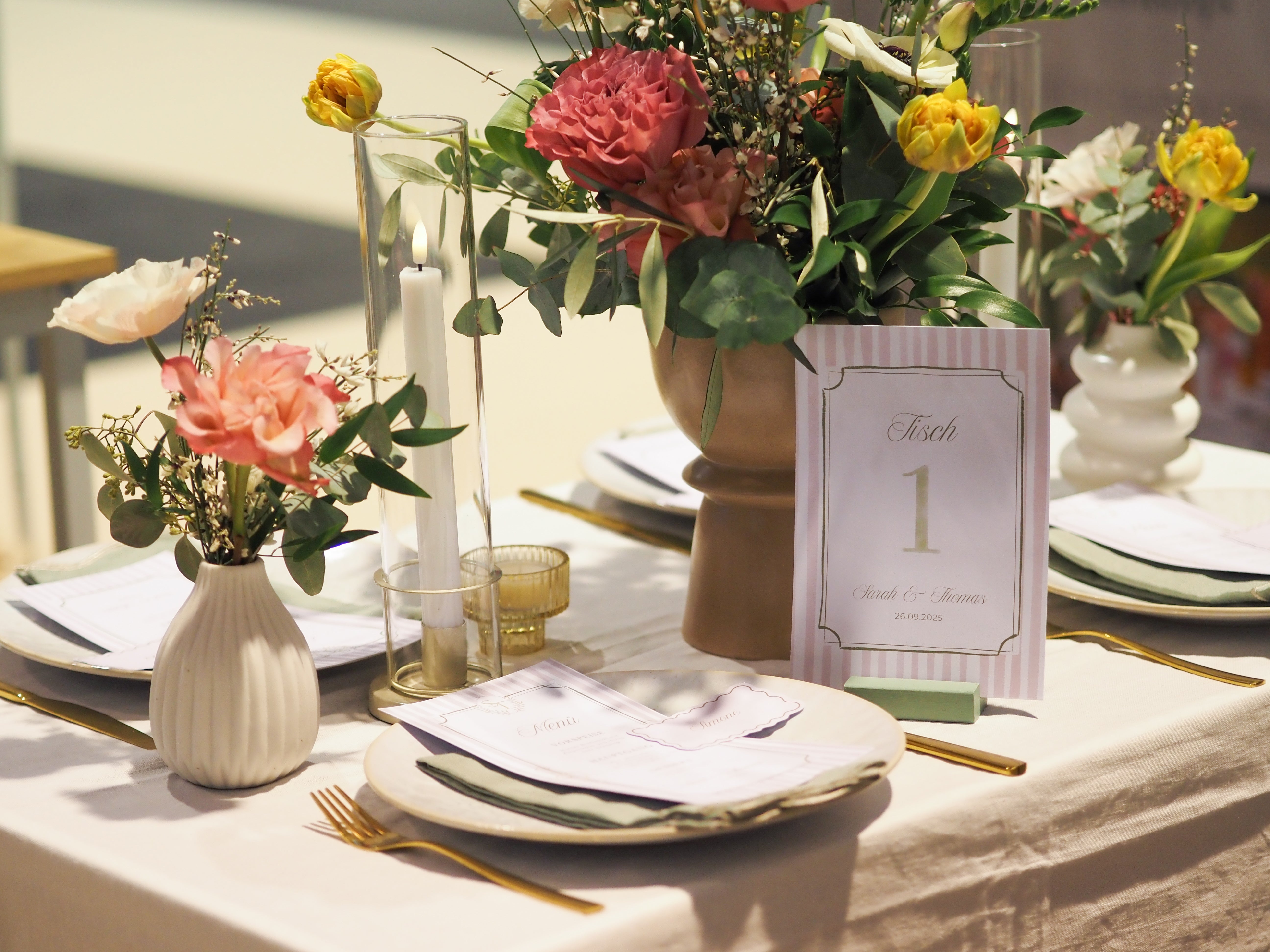Decorative table setting with flowers, candles, a menu and a table number card.