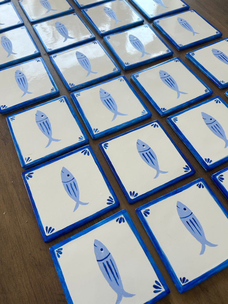 Set of handpainted tiles with sardine illustrations.